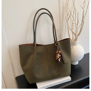 Close-up of olive green matte tote bag with elegant wooden bead tassel and side stitching
