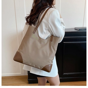 Detail of khaki nylon tote bag with brown leather base reinforcement and slender straps