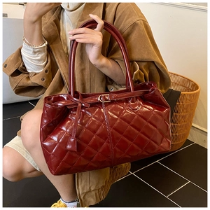 Close-up of a large dark red quilted patent leather tote bag with glossy finish and buckle