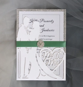 Detail of laser-cut wedding invitation with Mr & Mrs heart, green ribbon and rhinestone