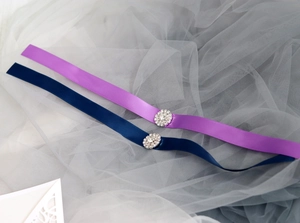 Nahaufnahme eleganter Satinbänder in Lila und Marineblau mit funkelnden Strassblumenmitten