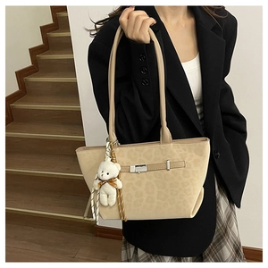 Detail of beige leopard-embossed tote bag featuring a silver buckle and cute plush bear charm