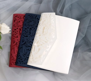 Macro view of laser-cut floral invitations in red, navy blue, and cream paper