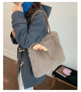 Brown faux fur tote bag with croissant charm worn on shoulder in a bright room