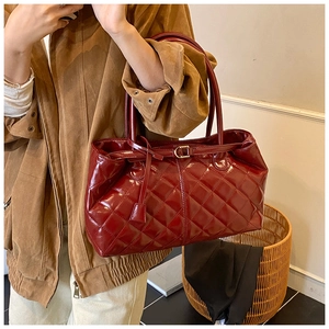 Détail de la texture en similicuir brillant rouge foncé matelassé de ce sac cabas