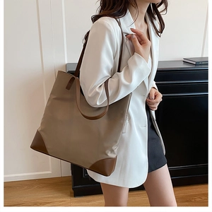 Side view of large khaki tote bag with brown leather patches on a female model