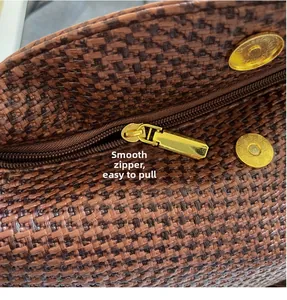 Detail of smooth gold zipper and magnetic buckle on brown woven hobo shoulder bag