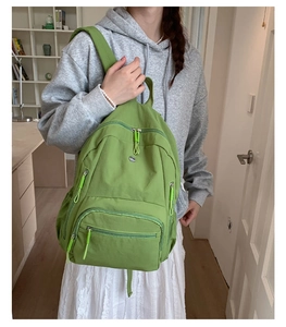 Seitenansicht eines matcha-grünen Nylon-Rucksacks mit mehreren Schichten und Berg-Logo