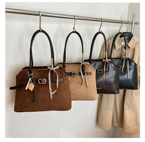 Detail view of four suede tote bags with decorative belts and plaid ribbons on hangers