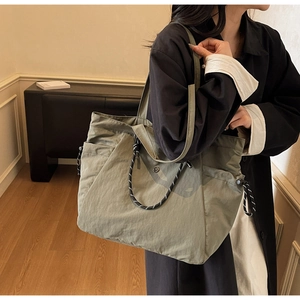 Dettaglio della borsa tote in nylon verde oliva con tasca laterale e manico intrecciato