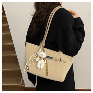 Detail of beige leopard print tote bag in matte finish with a plush bear pendant