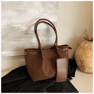 Detail of a brown suede tote bag with a matching pouch and elegant gold hardware buckle