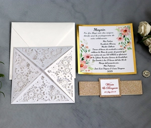 Detail of laser cut lace wedding invitation with gold glitter band and floral inner card