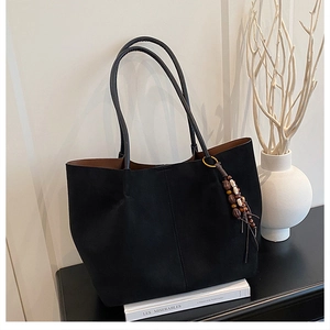 Detail of black suede tote bag with ethnic beaded tassel and spacious interior view