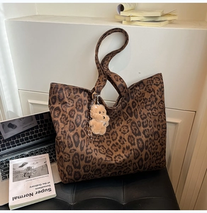 Detail view of leopard print tote bag with plush bear charm and spacious inner compartment