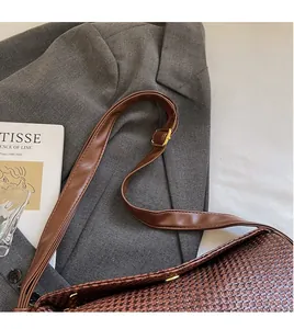 Detail showing brown woven bag texture with adjustable leather strap on gray blazer