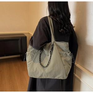Dettaglio della borsa tote in tela verde oliva con tasca laterale e corde decorative