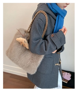 Detail of plush tote bag with braided handle and croissant charm in khaki faux fur