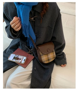 Detail of vintage saddle bag with brown leather and plaid stitching styled with a winter coat