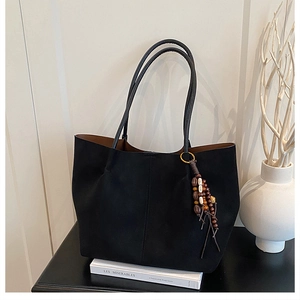 Minimalist black tote bag with wooden bead tassel shown in a lifestyle scene setting