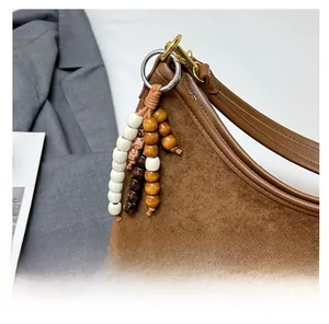 Detail of brown suede tote bag featuring a leather brand tag and vintage wooden bead charm