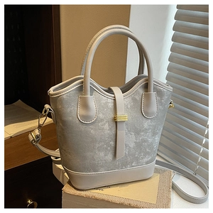 Détail du sac seau gris texturé marbre avec boucle dorée sur un décor intérieur élégant