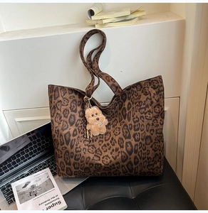Detailed view of leopard print tote bag with plush bear charm in a lifestyle setting