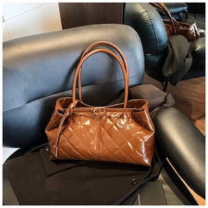 Gros plan d'un sac cabas marron matelassé en cuir verni avec une finition brillante