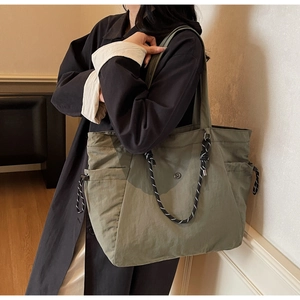 Dettaglio della borsa tote in nylon verde militare con tasche laterali e coulisse intrecciata