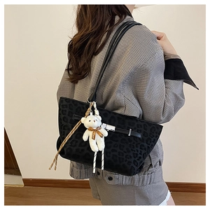 Close-up of black leopard print tote bag featuring a cute white teddy bear charm