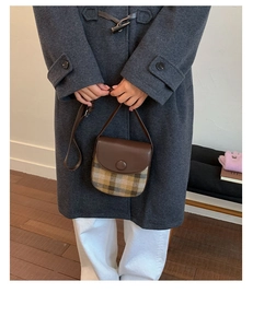 Detailed view of vintage plaid saddle bag with brown leather flap and stylish crossbody strap