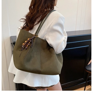Detail of olive green suede tote bag featuring a wooden bead tassel and large capacity
