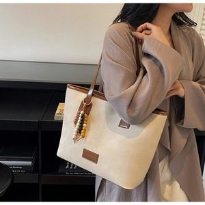 Détail du sac fourre-tout en toile beige avec bordure en cuir et glands perlés
