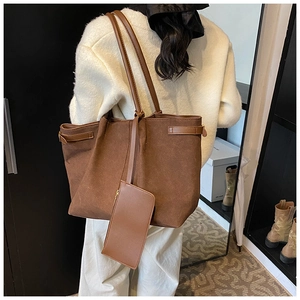 Detail van grote bruine matte shopper met bijpassend etui met ritssluiting op model schouder