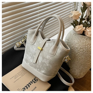 Détail du sac seau en velours gris clair avec boucles dorées et bandoulière