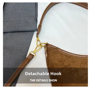 Detail of gold metal detachable hook and brown suede shoulder bag with clean stitching