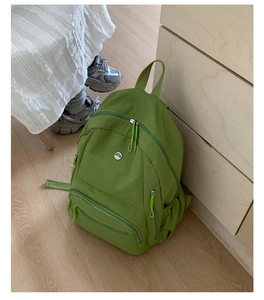 Detailansicht eines grünen Nylon-Rucksacks mit mehreren Reißverschlusstaschen für Reisen