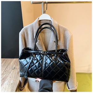 Détail du sac cabas matelassé noir brillant avec boucles dorées et doubles poignées