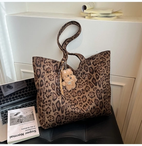 Leopard print velvet tote bag shown with laptop and cute teddy bear charm on leather seat
