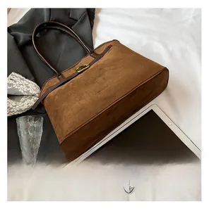 Detailed shot of brown suede tote bag with leather belt strap and gold metal buckle