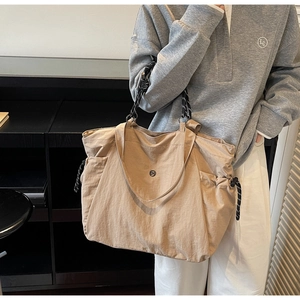 Dettaglio della borsa tote kaki con tasche laterali a coulisse e manici in corda intrecciata