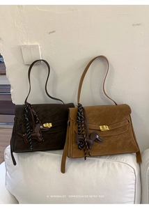 Detail of retro suede shoulder bags featuring gold turn-lock closure and dog charm