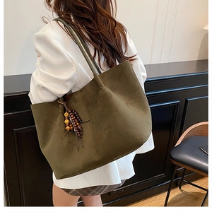 Detailed back view of a moss green suede tote bag with decorative dark wooden beads