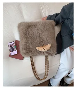 Detail of light brown fuzzy tote bag with plush croissant charm and woven handles