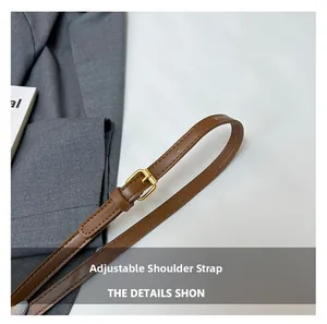 Detailed view of adjustable brown leather shoulder strap with gold metal buckle hardware