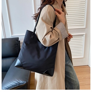 Detail of black waterproof nylon tote bag with leather corners and slim shoulder straps