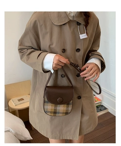 Detail of vintage brown plaid saddle bag with leather flap and round buckle detail