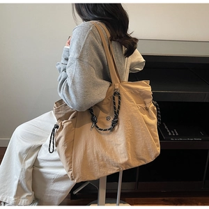 Vista dettagliata della borsa tote in tela kaki con coulisse a contrasto sulla modella