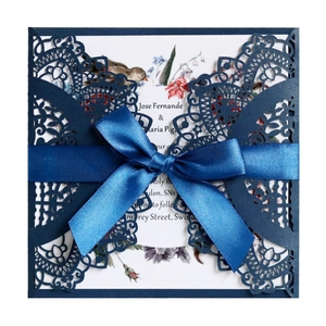 Navy blue laser-cut wedding invitation with lace patterns and a silk ribbon bow