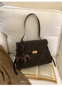 Detail of dark brown retro briefcase with gold buckle and dachshund leather charm